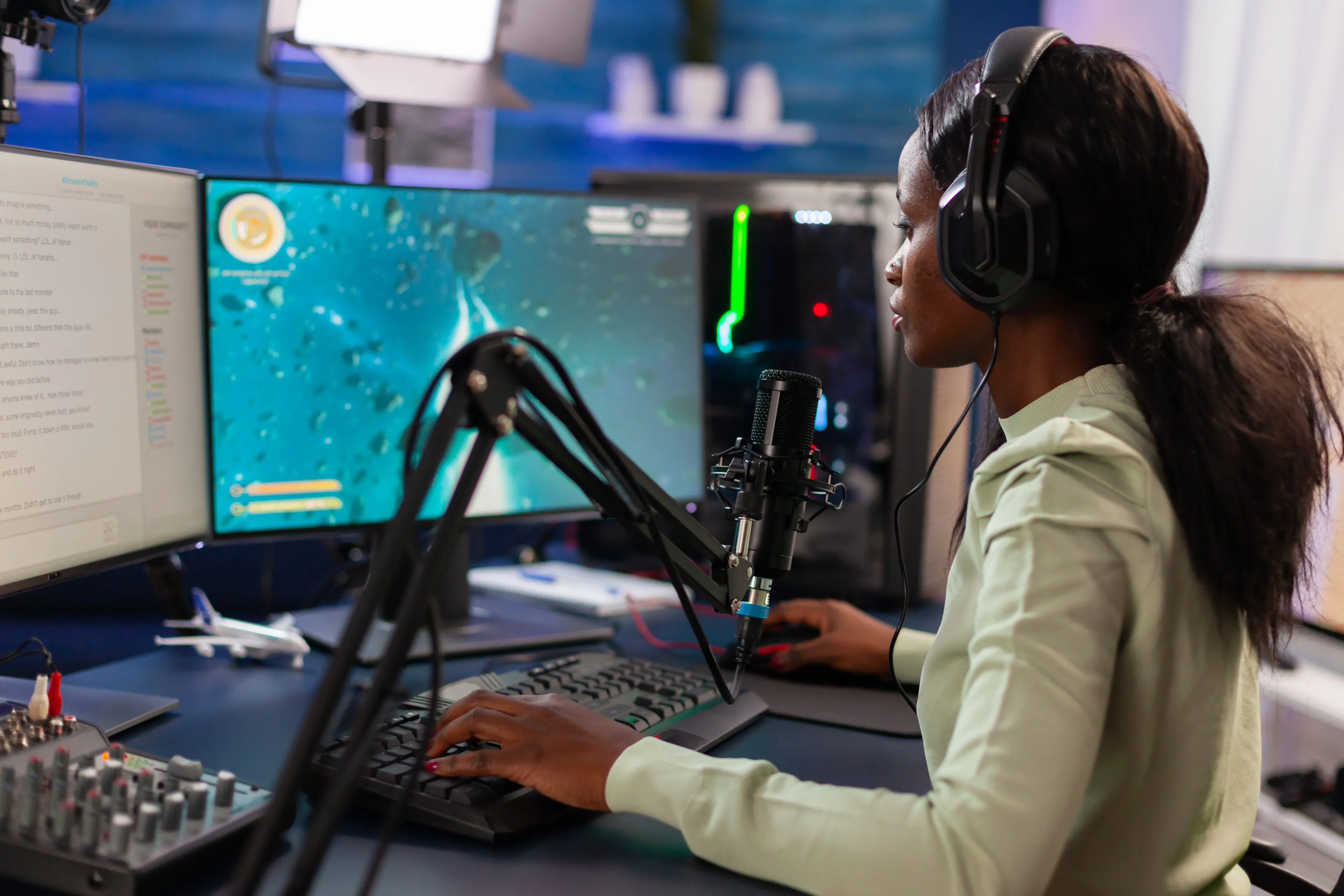 streamer at desk with dual monitors keyboard microphone and headphones