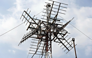 Large rooftop broadcast antenna structure under cloudy sky