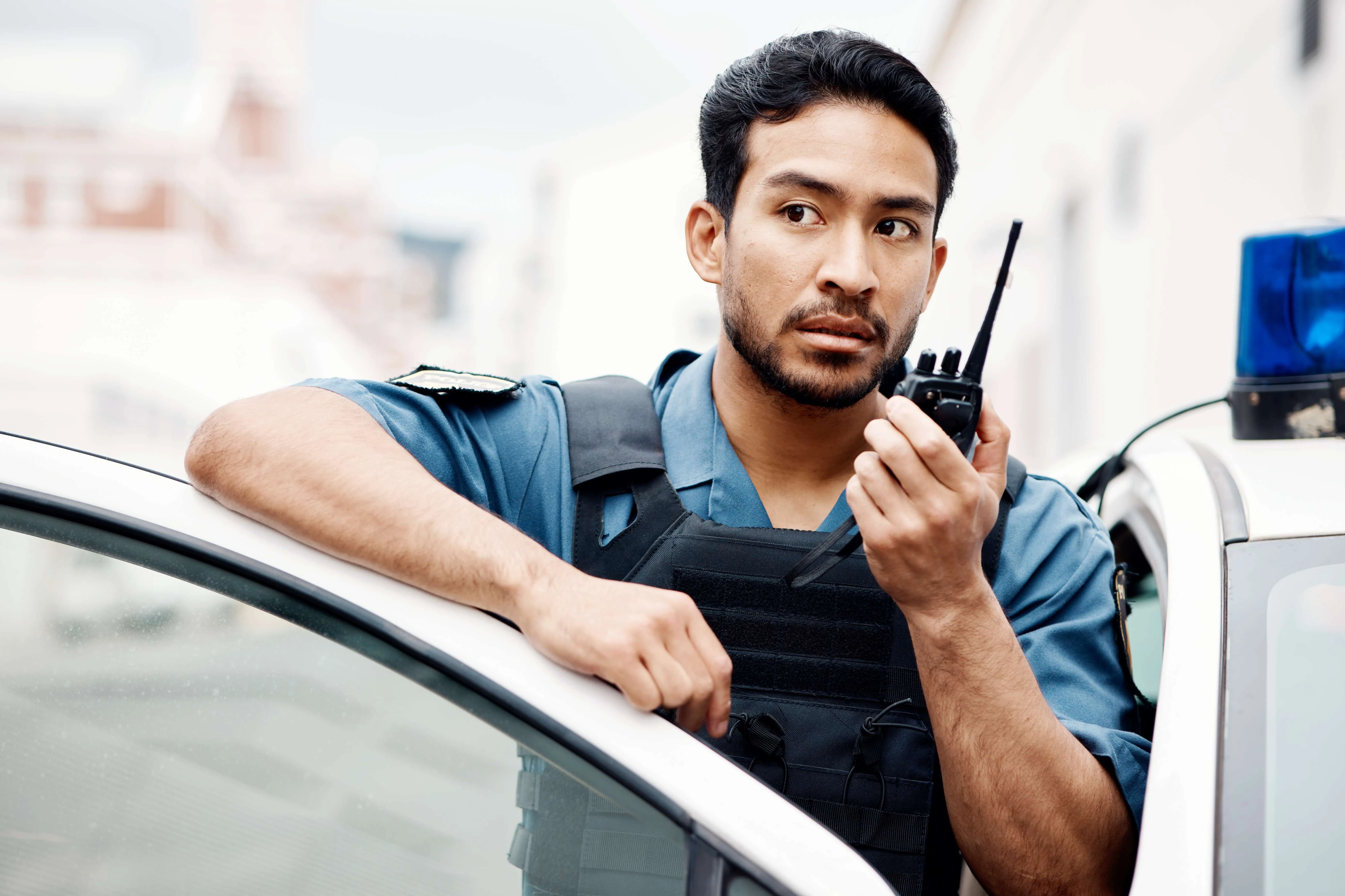 asian-man-police-and-walkie-talkie-for-radio-in-c-2025-04-05-19-14-35-utc Police officer using walkie talkie beside patrol car