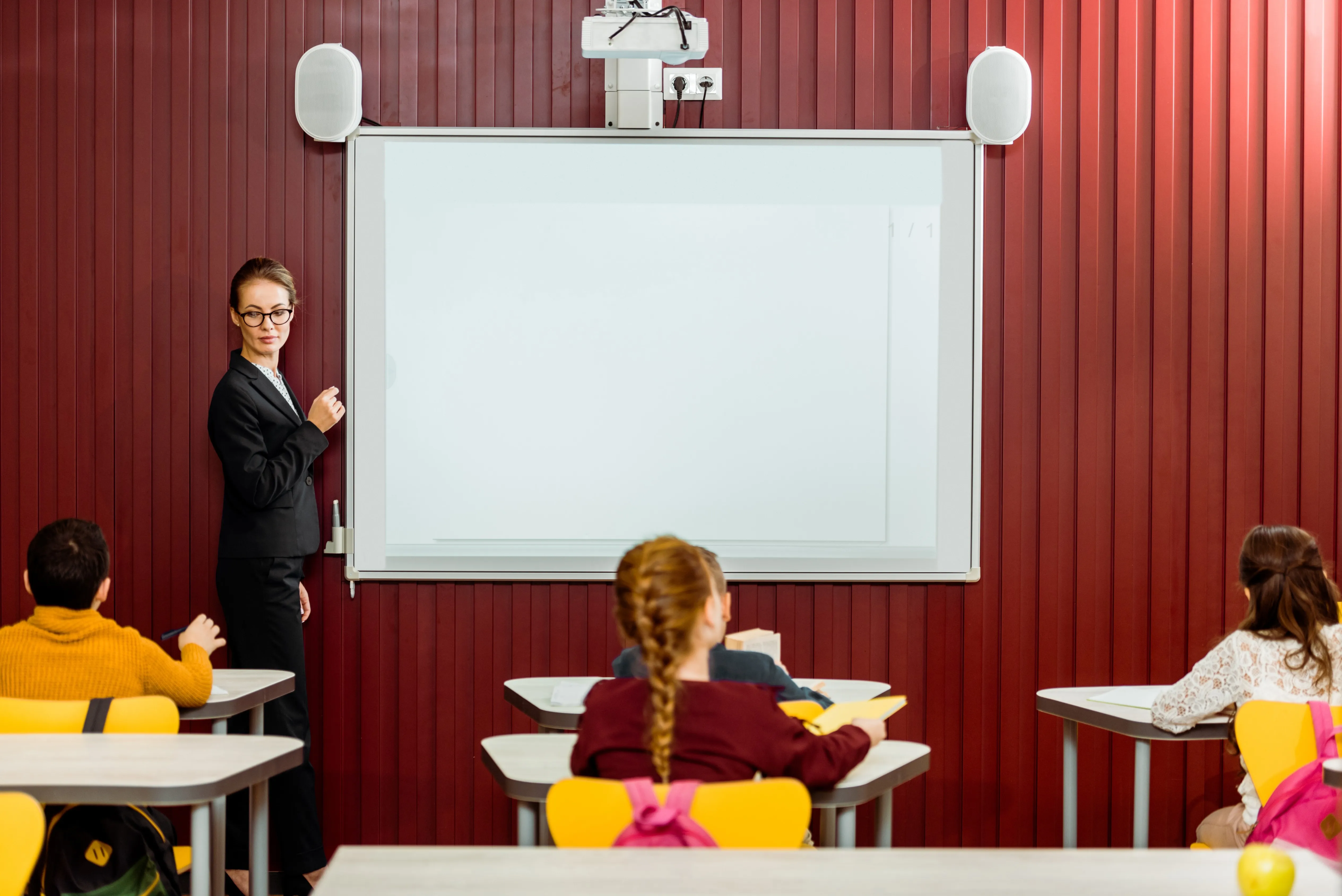 Teacher at whiteboard with mounted projector teaching young children
