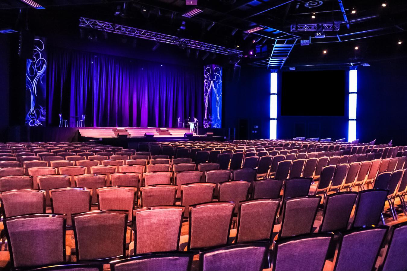 stage with rows of chairs purple backdrop and side video pillar