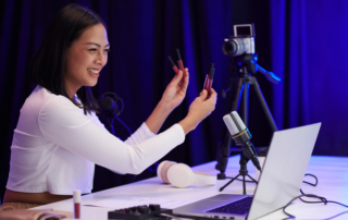 Woman livestreaming beauty product demo with microphone laptop and camera