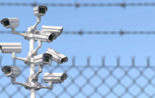 Cluster of surveillance cameras mounted near barbed wire fence