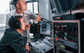 Podcasters in studio with microphone mixing desk and mounted monitors