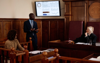 team reviewing documents around a table facing a video call on a monitor