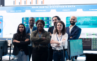 diverse team posing in front of computer monitors