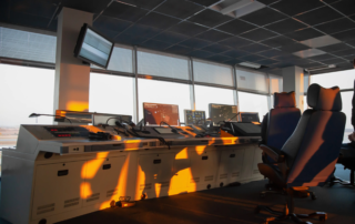 Empty air traffic control room with multiple radar monitors and swivel chairs