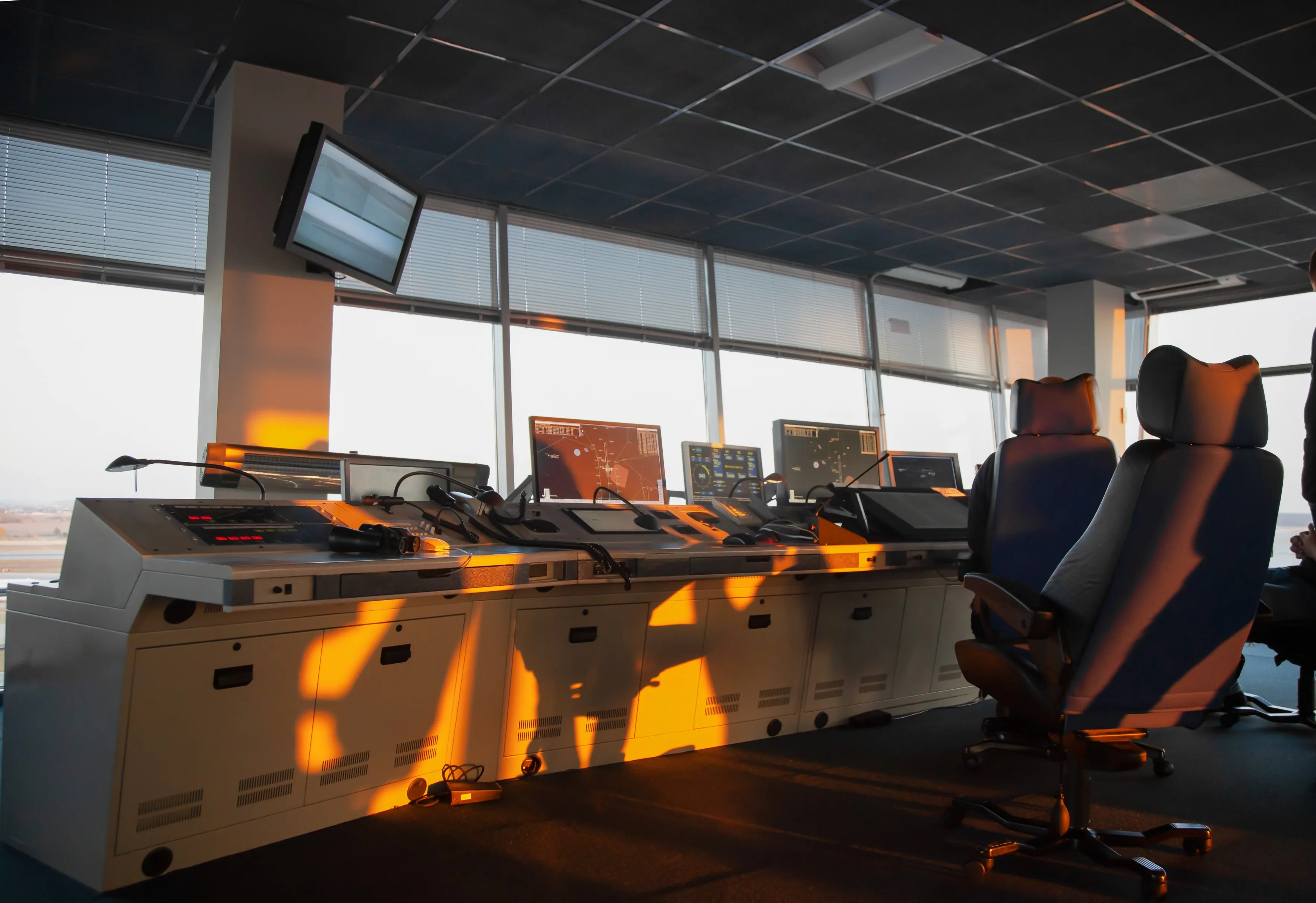 Empty air traffic control room with multiple radar monitors and swivel chairs