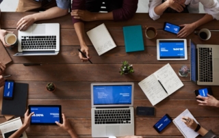 team around a table with laptops tablets and smartphones