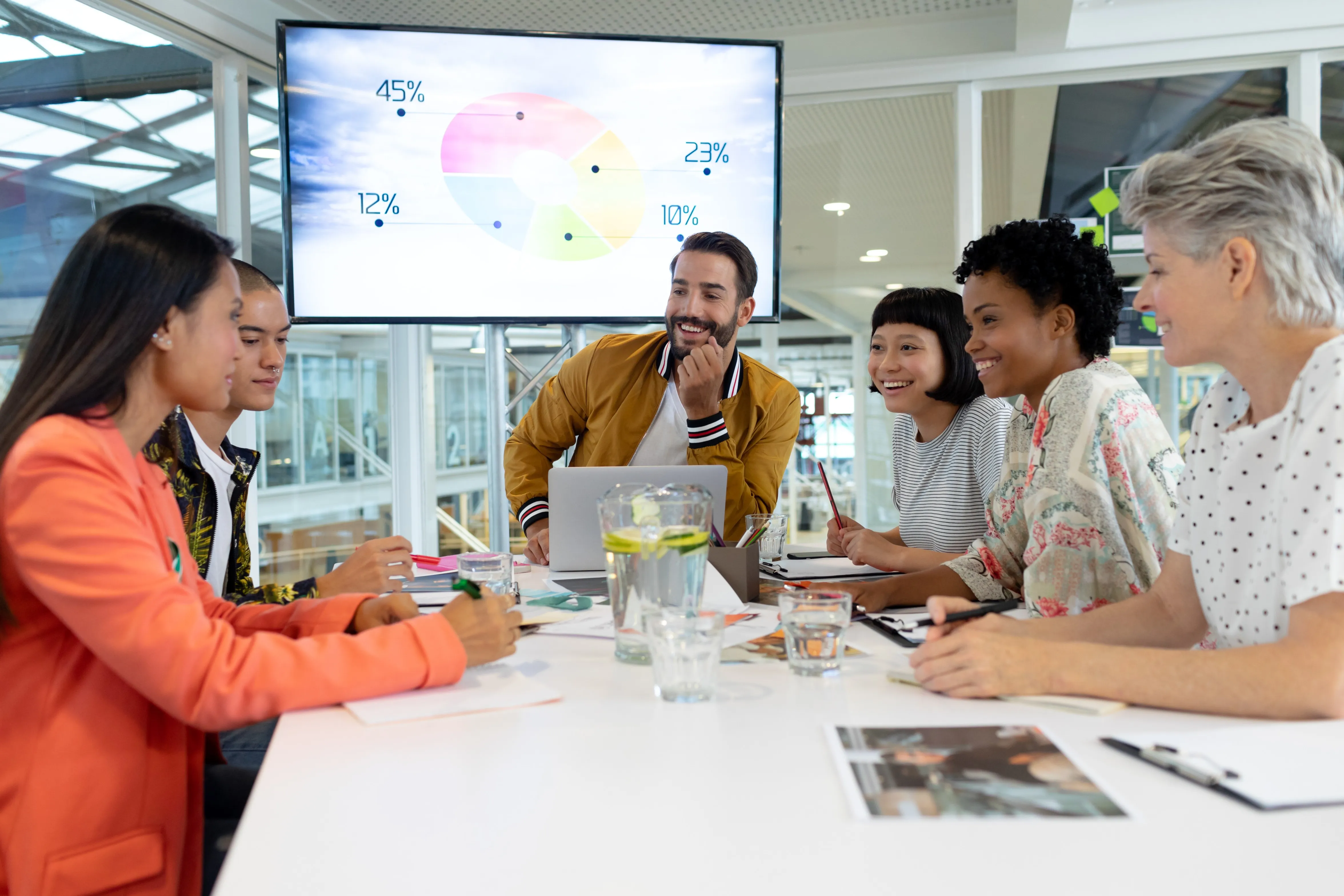 group of people at table with wall monitor and laptop device monitor laptop