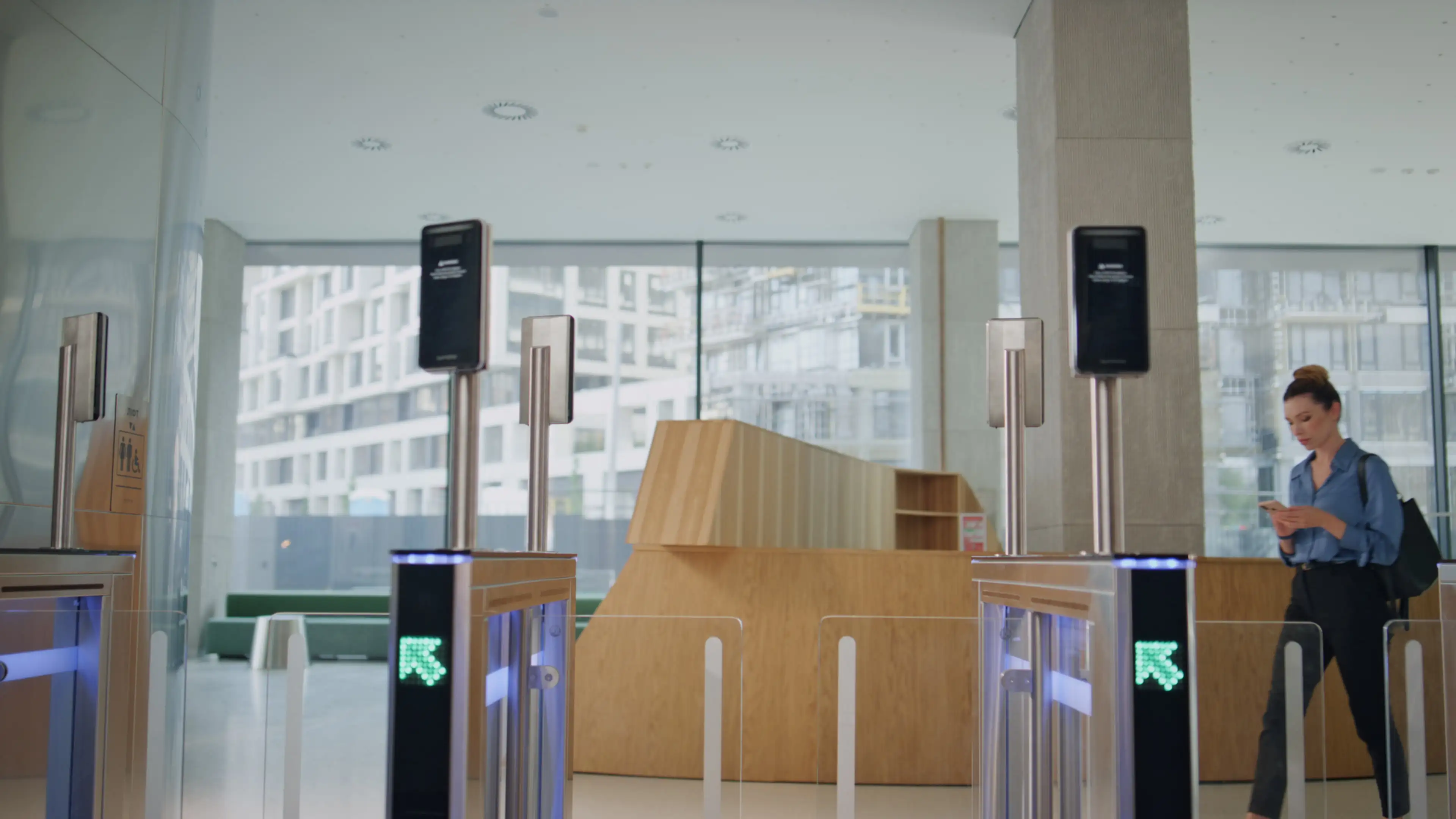Woman walking through automated security gate using phone