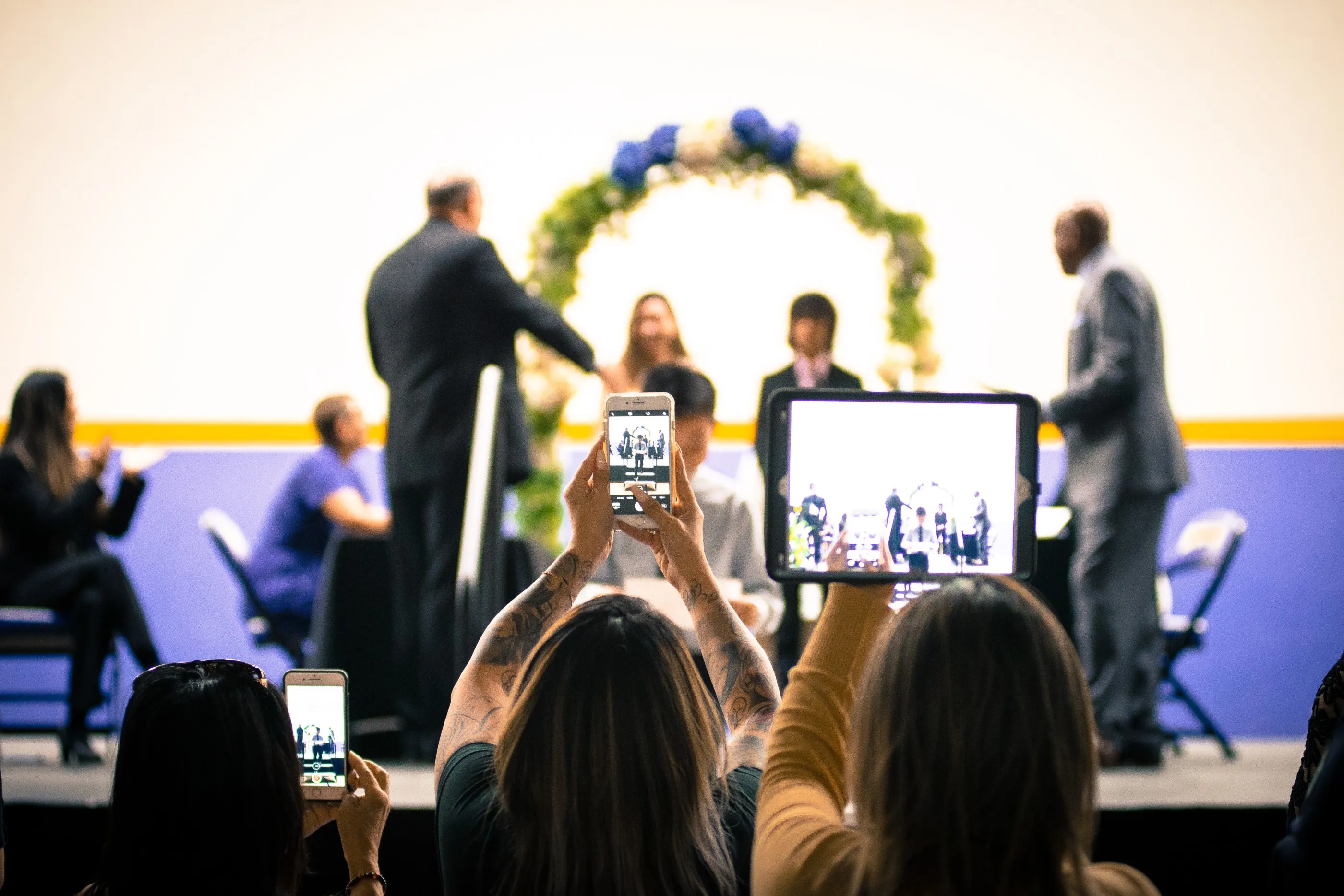 Audience recording stage ceremony with smartphones and tablet