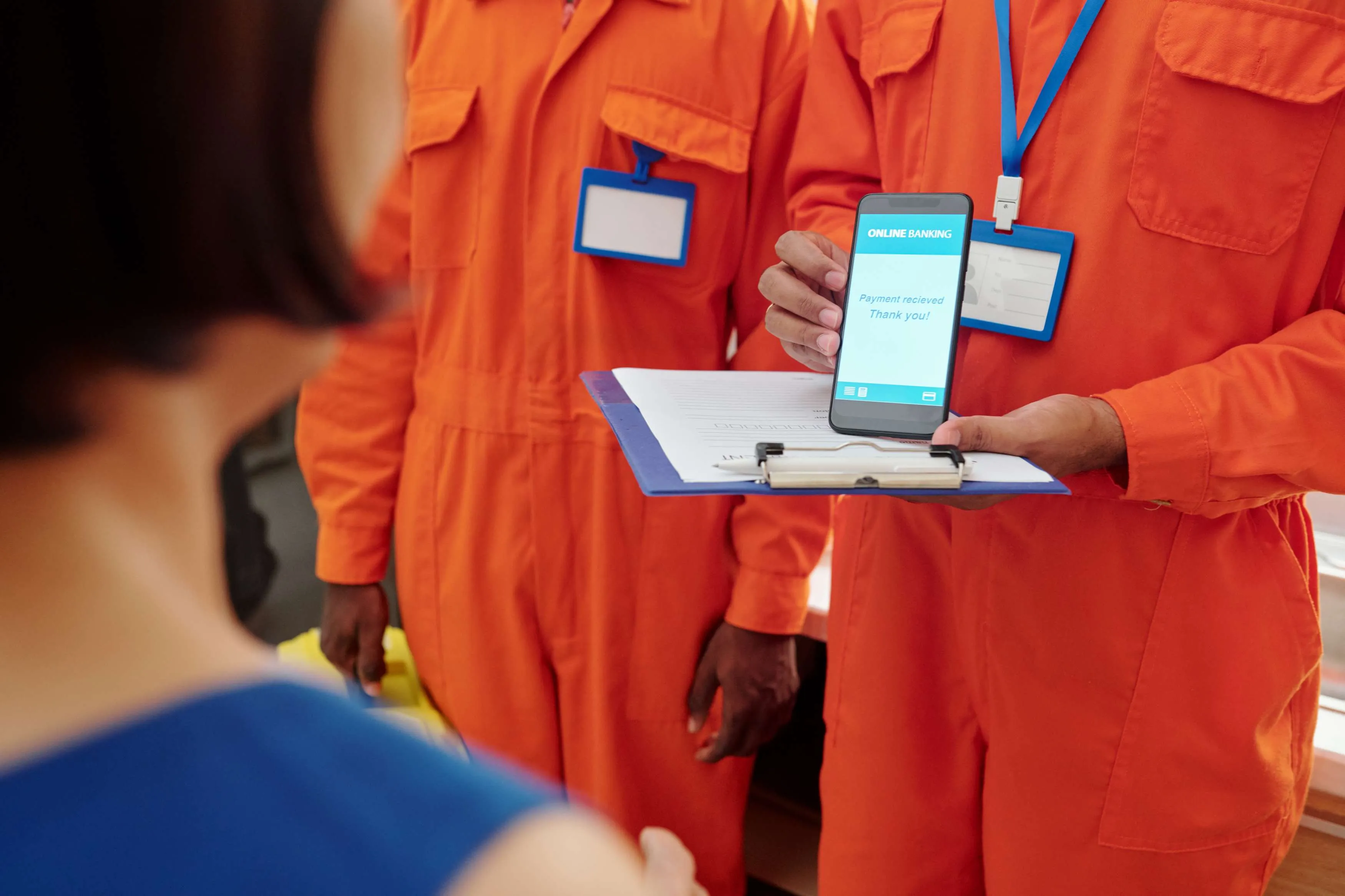 pumbers-receiving-payment-for-service-2025-01-29-09-06-01-utc Person in orange jumpsuit showing phone with online banking screen