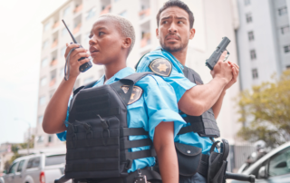 two officers back to back one holding radio device and one drawing handgun