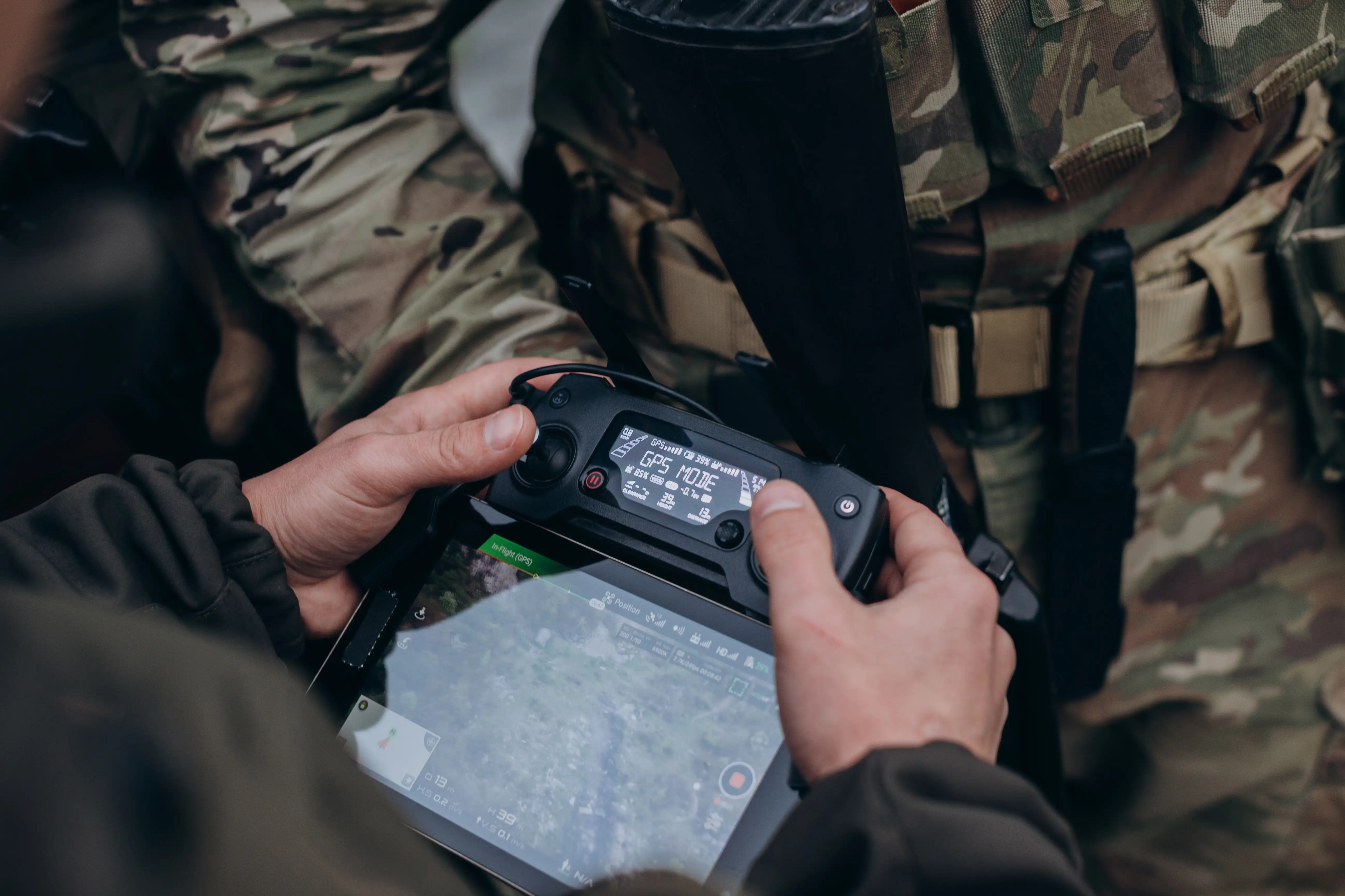 Soldier holding drone controller with GPS mode on tablet screen