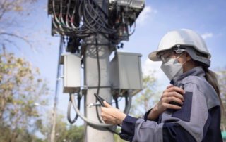field technician in a hard hat using a walkie‑talkie