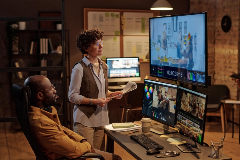 Designer and Project manager working on editing videos with 3 screens