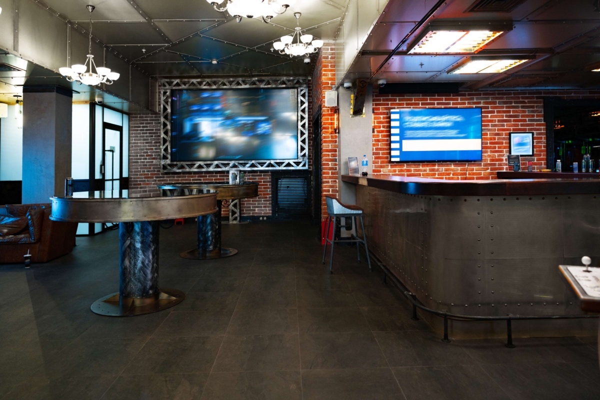 interior-of-a-dark-pub-loft-interior-2025-02-25-11-26-46-utc (1) industrial bar lounge with metal tables chandeliers brick wall bar counter and wall mounted display screens