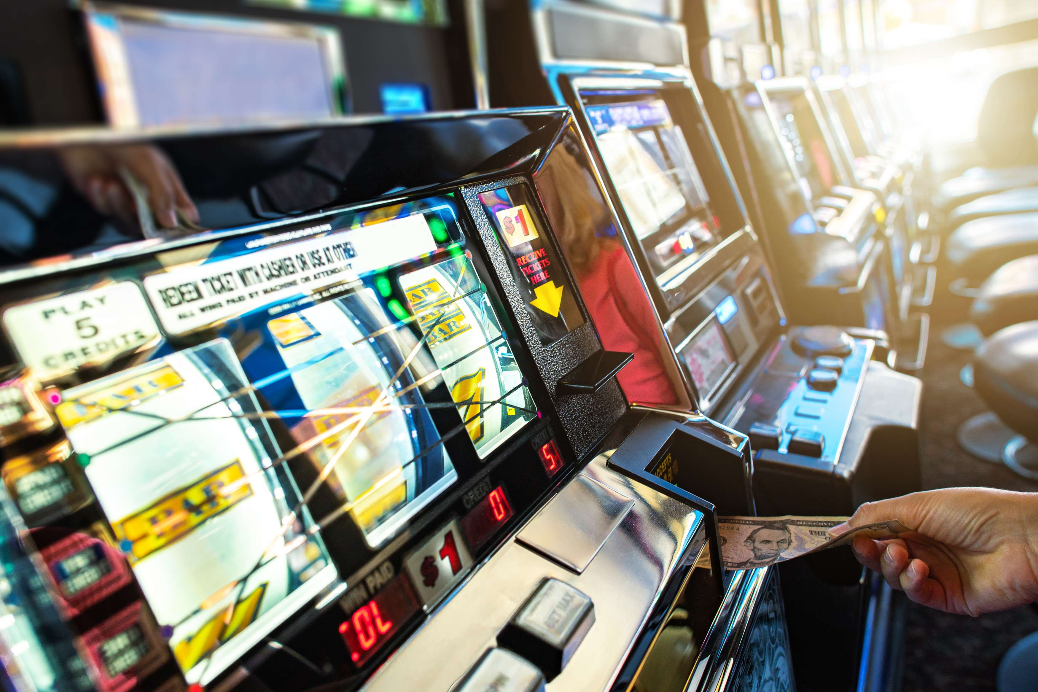 Las Vegas slot machine player inserting banknote