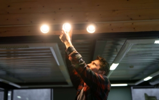 a man replacing a lightbulb on ceiling