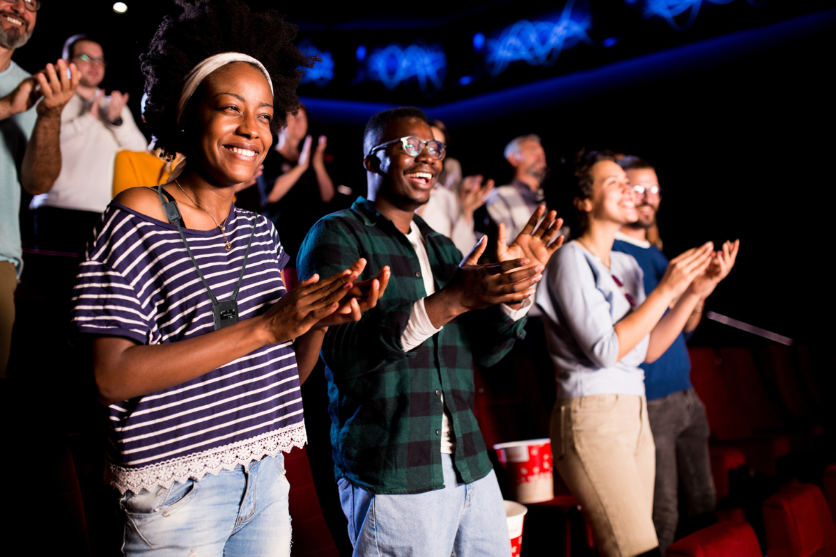 Happy couple applauding with the rest of the audience at the cinema