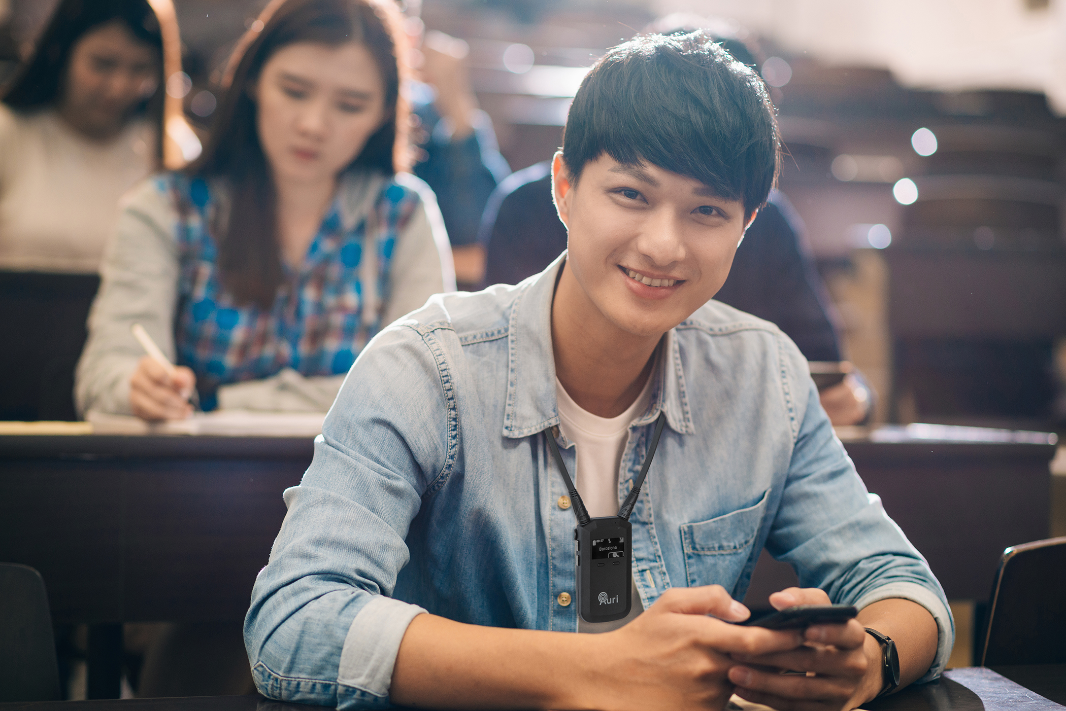 Smiling Taiwanese student with mobile phone in lecture hall.